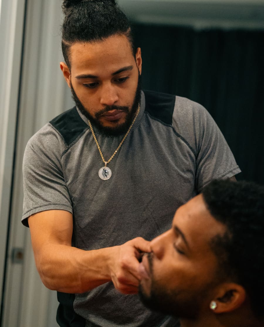 The Shaving Angel shaping a client's moustache line with focused attention.